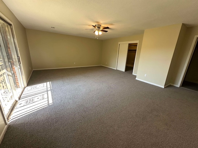 empty room with a textured ceiling, dark carpet, and ceiling fan