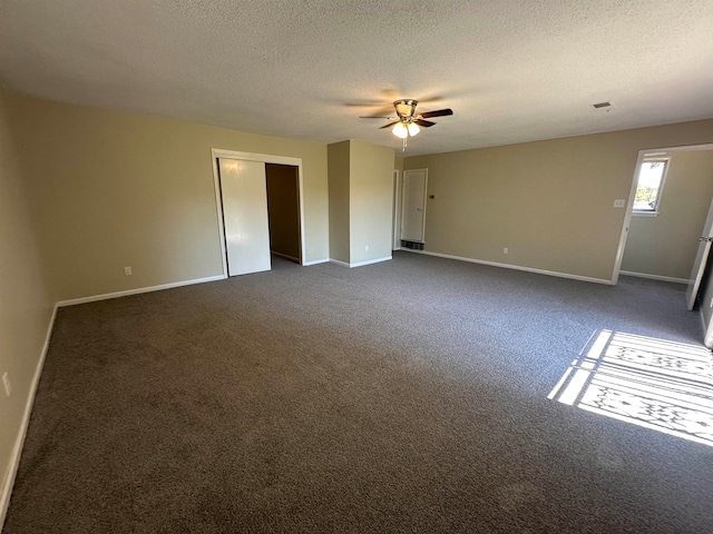 unfurnished room featuring ceiling fan, a textured ceiling, and dark carpet