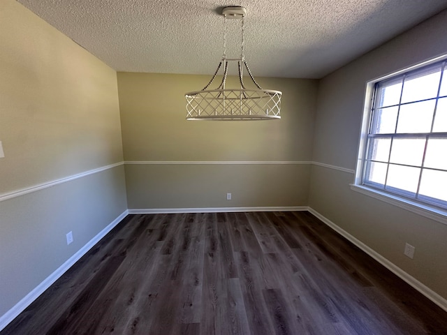 unfurnished dining area featuring a textured ceiling and dark hardwood / wood-style flooring