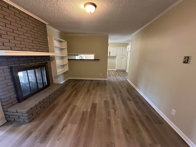 unfurnished living room with hardwood / wood-style floors, crown molding, a brick fireplace, and a textured ceiling