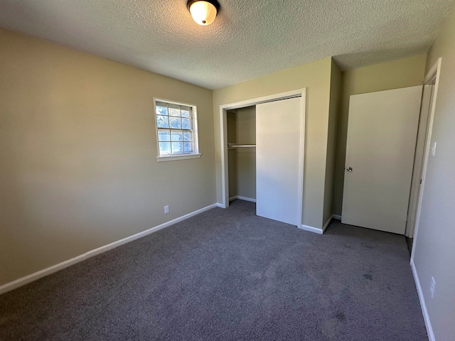 unfurnished bedroom with a closet, a textured ceiling, and dark colored carpet