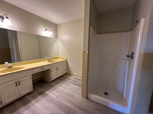 bathroom featuring vanity, hardwood / wood-style floors, a textured ceiling, and walk in shower