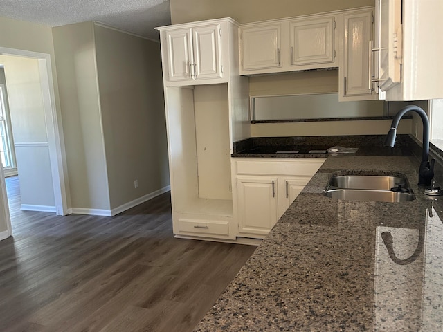 kitchen featuring sink, a textured ceiling, white cabinetry, dark stone countertops, and dark hardwood / wood-style floors