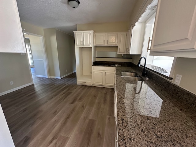 kitchen with dark hardwood / wood-style floors, dark stone countertops, sink, white cabinetry, and a textured ceiling