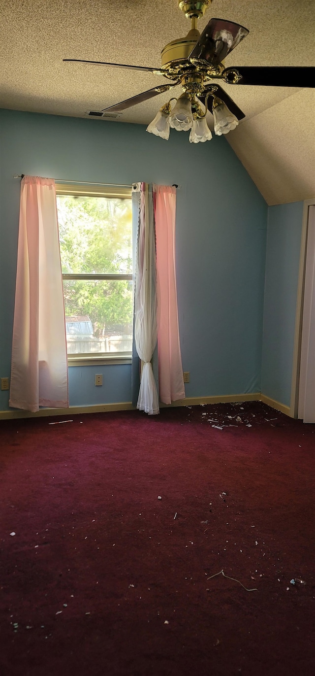 empty room featuring a textured ceiling, ceiling fan, carpet, and vaulted ceiling