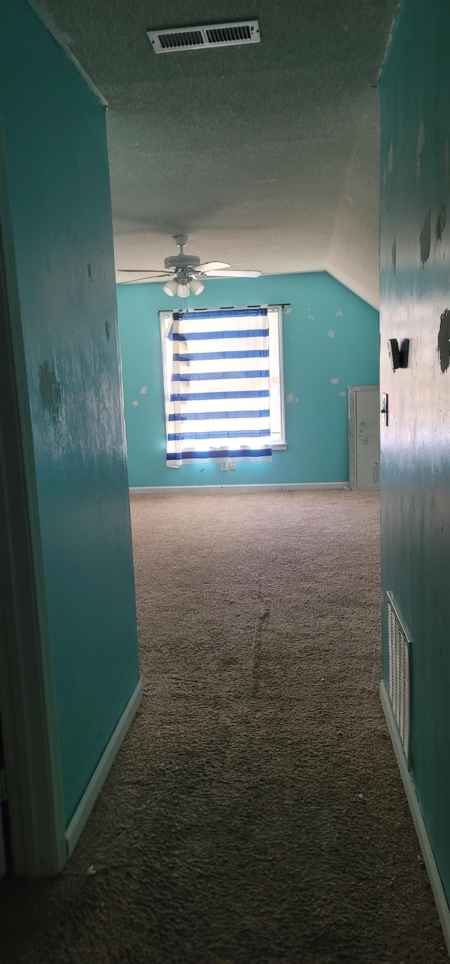 corridor featuring a textured ceiling, vaulted ceiling, and carpet floors