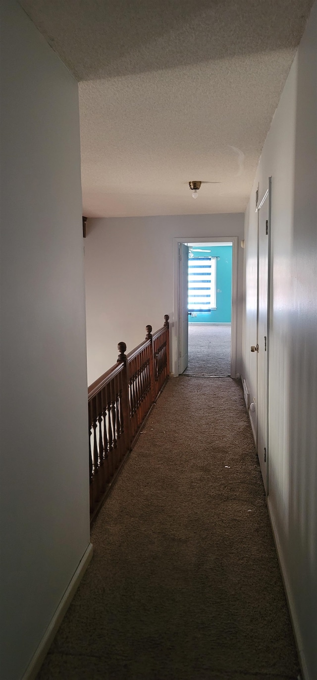 hall with a textured ceiling and carpet flooring