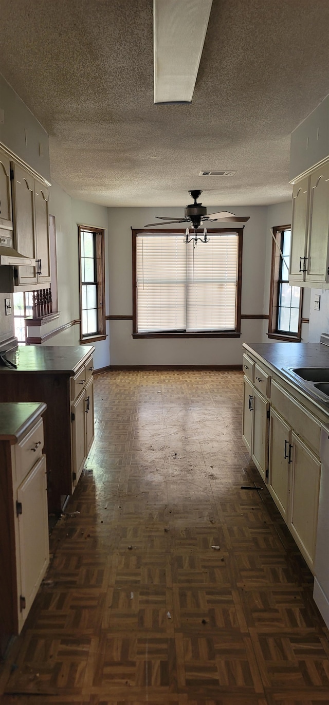 kitchen featuring ceiling fan, cream cabinets, and dark parquet flooring