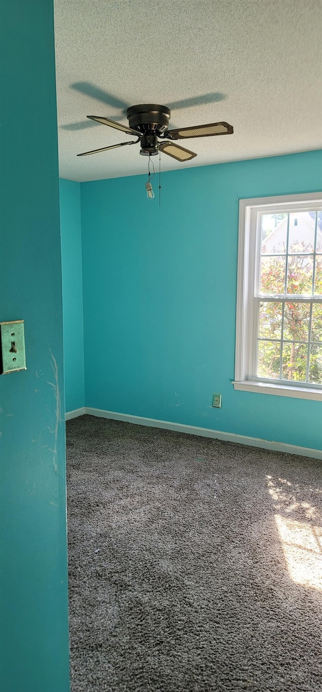 carpeted spare room featuring ceiling fan and a textured ceiling