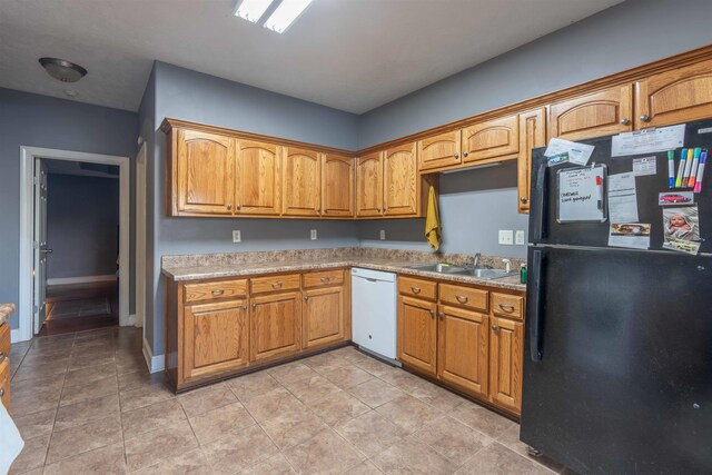 kitchen with black fridge, white dishwasher, light tile patterned flooring, and sink