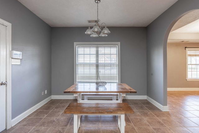 unfurnished dining area with tile patterned flooring, plenty of natural light, and a notable chandelier