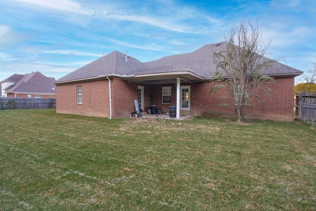 back of property with a yard and a patio area