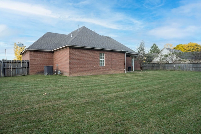 rear view of property featuring cooling unit and a lawn