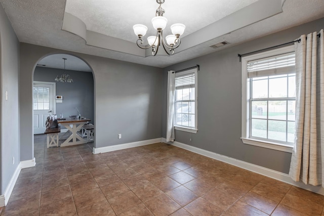 unfurnished room with tile patterned flooring, a textured ceiling, and an inviting chandelier