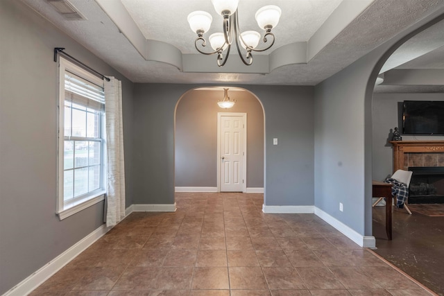 tiled dining room featuring a textured ceiling, a tile fireplace, and a notable chandelier