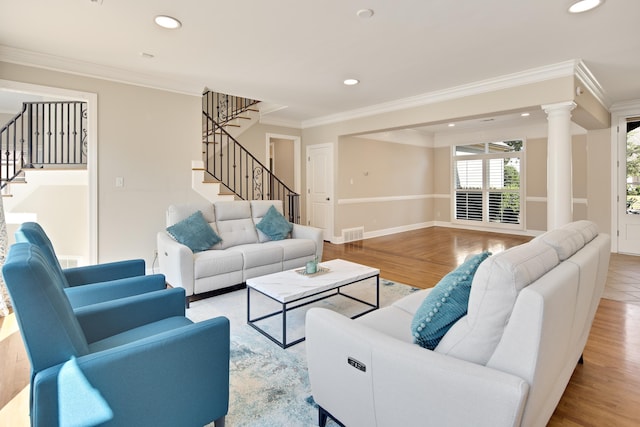 living room featuring light hardwood / wood-style flooring, crown molding, and decorative columns