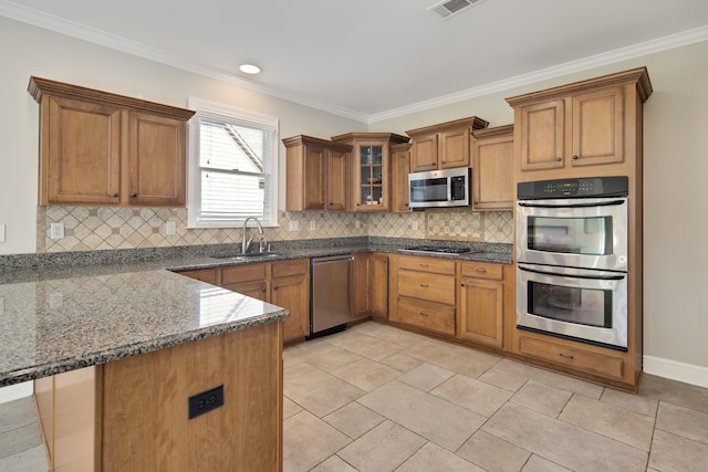 kitchen with appliances with stainless steel finishes, kitchen peninsula, ornamental molding, and sink