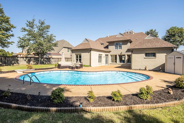 view of swimming pool with a shed, a patio, and a diving board