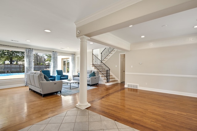 unfurnished living room featuring ornamental molding, light wood-type flooring, and decorative columns