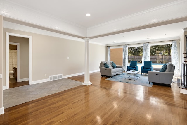 living room with decorative columns, light hardwood / wood-style flooring, and crown molding