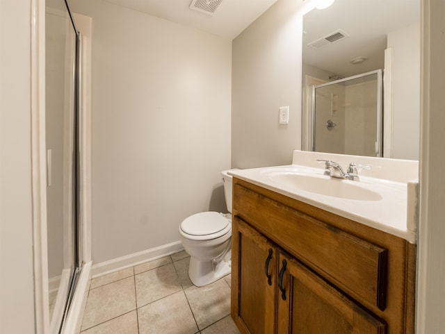 bathroom with a shower with door, vanity, toilet, and tile patterned floors