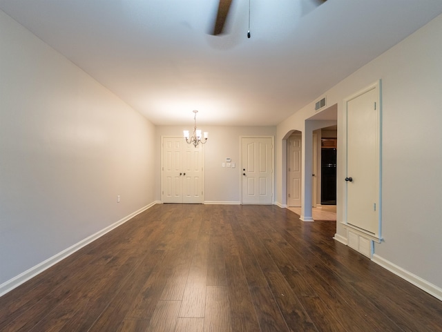 empty room with dark wood-type flooring and ceiling fan with notable chandelier