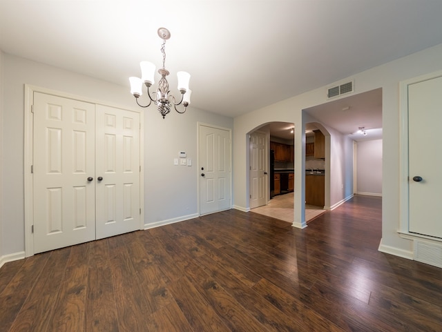 unfurnished dining area with a chandelier and dark hardwood / wood-style floors