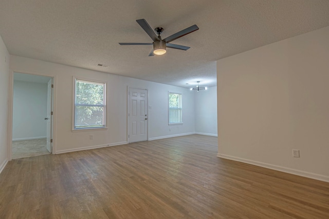 unfurnished living room featuring plenty of natural light, ceiling fan with notable chandelier, and hardwood / wood-style floors