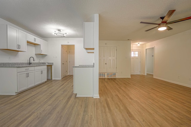 kitchen featuring ceiling fan, a textured ceiling, light wood-type flooring, and white cabinets