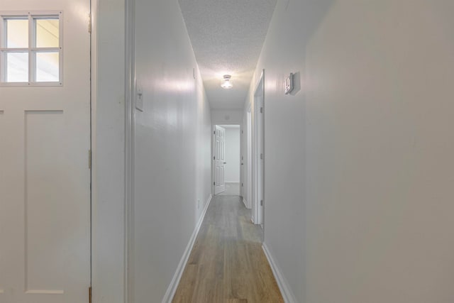 corridor featuring a textured ceiling and light wood-type flooring