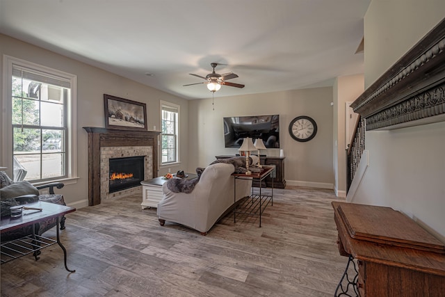 living room featuring a wealth of natural light, light hardwood / wood-style flooring, a fireplace, and ceiling fan