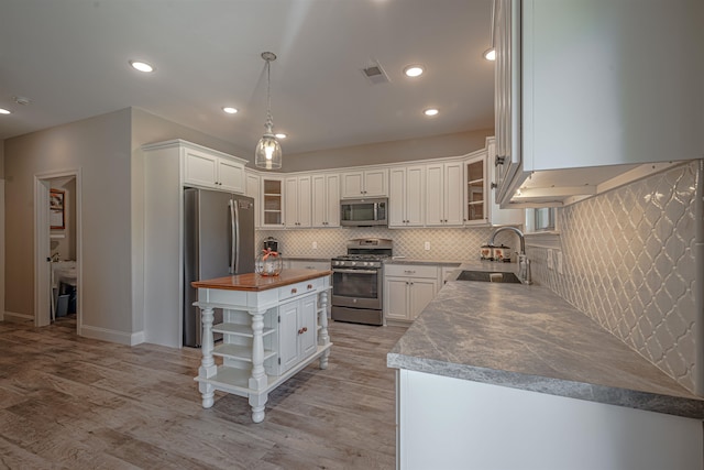 kitchen featuring white cabinets, appliances with stainless steel finishes, sink, a center island, and wooden counters