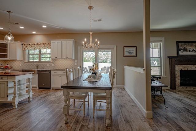 dining space featuring sink, a healthy amount of sunlight, light hardwood / wood-style flooring, and a fireplace