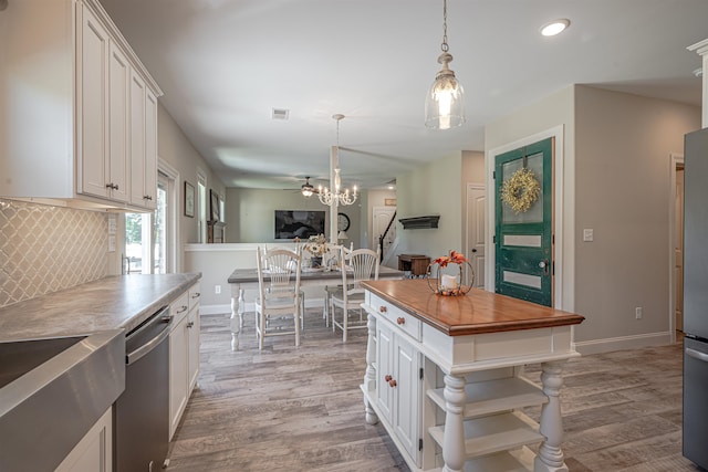 kitchen featuring decorative light fixtures, stainless steel dishwasher, and white cabinets