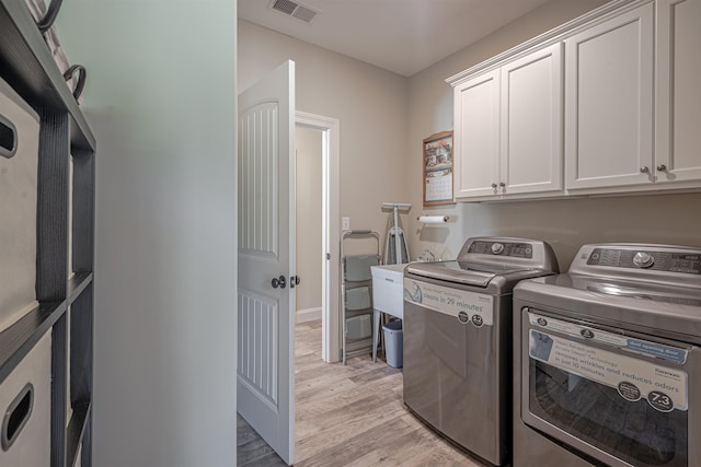 laundry room with independent washer and dryer, cabinets, and light hardwood / wood-style floors