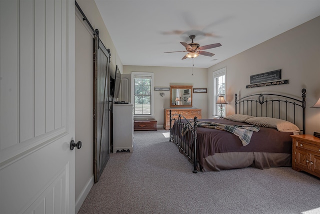 bedroom with a barn door, carpet, and ceiling fan