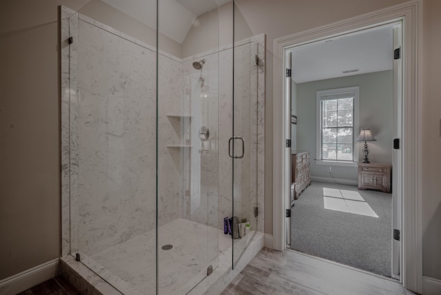 bathroom with a shower with door, lofted ceiling, and wood-type flooring