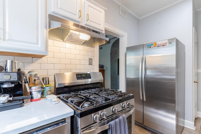 kitchen with tasteful backsplash, appliances with stainless steel finishes, white cabinets, ornamental molding, and light tile patterned floors