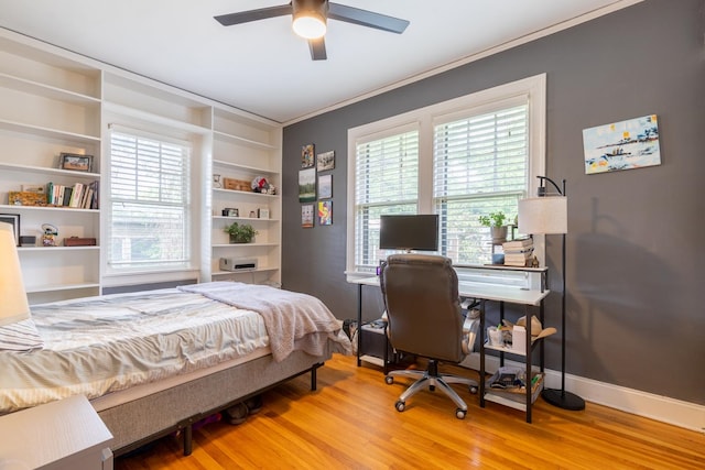 bedroom with ceiling fan, crown molding, multiple windows, and light wood-type flooring