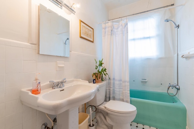 bathroom with toilet, shower / bath combo with shower curtain, and tile walls