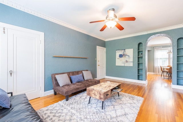 living room with ornamental molding, hardwood / wood-style floors, ceiling fan, and built in shelves