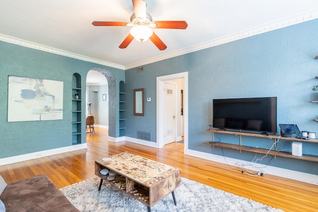 living room featuring crown molding, hardwood / wood-style flooring, ceiling fan, and built in shelves