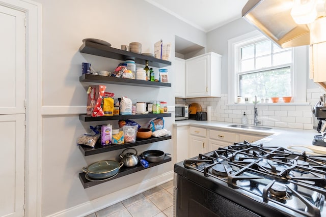 kitchen with black stove, backsplash, sink, light tile patterned flooring, and white cabinets