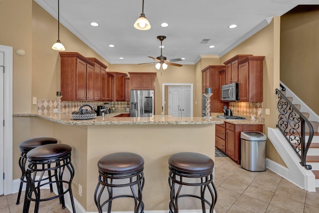 kitchen with stainless steel appliances, tasteful backsplash, kitchen peninsula, and hanging light fixtures