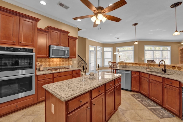 kitchen featuring a center island, appliances with stainless steel finishes, sink, and decorative light fixtures