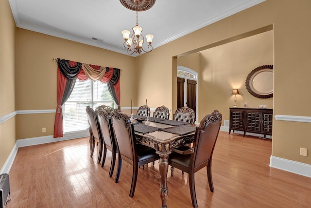 dining space featuring light hardwood / wood-style floors, crown molding, and a notable chandelier