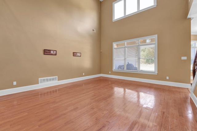 interior space with a high ceiling, plenty of natural light, and light wood-type flooring