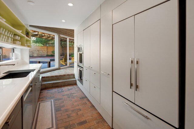 kitchen with vaulted ceiling, stainless steel appliances, sink, and white cabinets