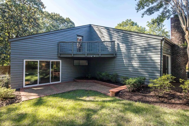 rear view of property featuring a yard and a balcony