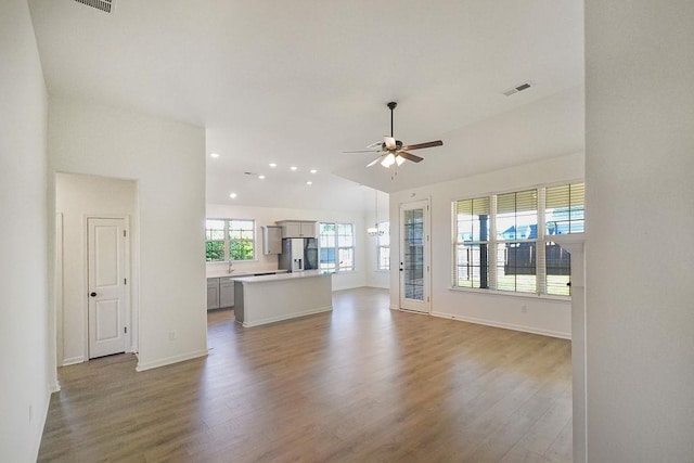 unfurnished living room featuring hardwood / wood-style flooring, sink, ceiling fan, and vaulted ceiling